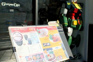 A Gundam robot and a menu welcome each customer to their tiny food shop.