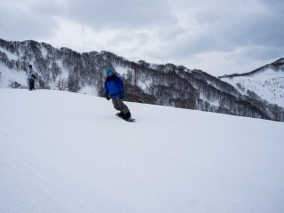 Snowboarder testing out his moves on the beginner&#39;s slope