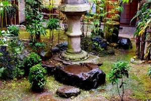 A lone stone lantern standing amidst a damp, mossy garden