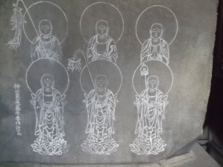 Six Buddhist figures are carved onto a large rock on an altar