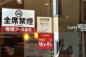 The sign of the cafe Veloce in Shibuya says, "No smoking but a smoking booth is available"