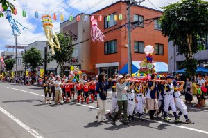 Children parade down the street carrying decorated dashi floats