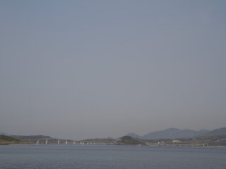 本土を遠望する; 角島大橋は海峡と鳩島 (はとしま) を横断するように架かっている