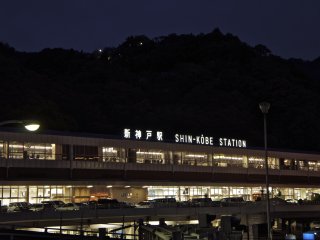 Cảnh về đêm của tàu điện hình con thoi Shin Kobe. Trạm nằm gần các khu định cư nước ngoài cũ ở Kitano-cho, và nếu bạn còn thời gian thì khu vực này sẽ khá tốt để thưởng thức bữa tối Pháp hoặc Ý ngon lành trước khi bạn rời khỏi Kobe.