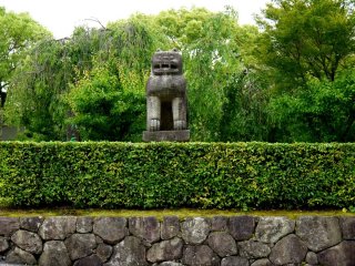Stone lion and trimmed hedges