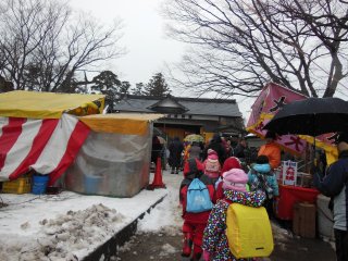 Children, parents, visitors, and residents pour into the shrine grounds to see the performance.