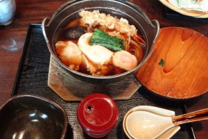 The nabeyaki udon is another tasty noodle dish. It is udon noodles with a variety of toppings, such as boiled egg, shrimp tempura, mushrooms, seasonal green vegetables, and fish paste.