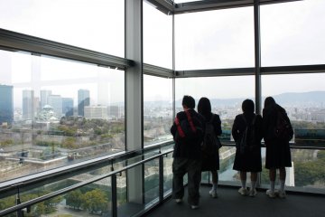 <p>แลปราสาท &gt; กลุ่มเด็กนักเรียนมัธยมปลายของญี่ปุ่นกำลังยืนดูปราสาทโอซาก้าและเมืองอันรุ่งเรืองในยุคปัจจุบันโดยรอบ ซึ่งบริเวณนี้คือกระจกใสตรงโถงบันไดเชื่อมชั้นที่เป็นหนึ่งในจุดชมวิวเมืองโอซาก้าอันแสนพิเศษและสวยงามไม่เหมือนใคร</p>