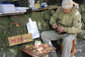 Um artesão local fazendo vários artigos a partir de bambu para venda
