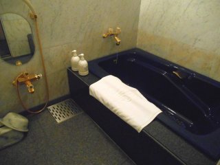Bathroom has a deep-blue bathtub and gold faucet.....how 80s!!