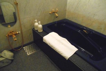 욕실에는 짙은 파란색 욕조와 금색 수도꼭지가 있다!