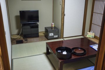 <p>The interior of the regular room, with tatami-matted floors, a television and a dining area.</p>