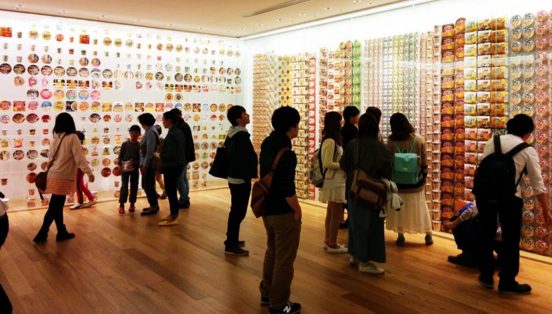 <p>Visitors browse the walls of past instant noodle package designs.&nbsp;</p>