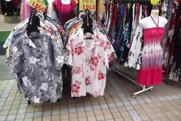 <p>There are lots of colorful shirts and dresses for sale</p>