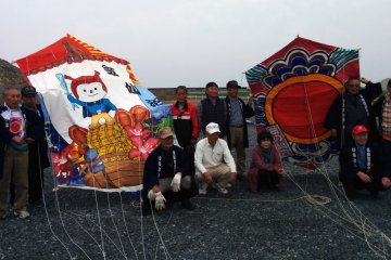 <p>The local Kesennuma&nbsp;kite association poses proudly next to their oversized kites</p>