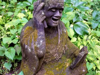 Statue of monk looking at address book and talking on a cell-phone