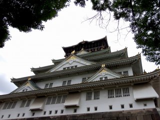 Sekarang Anda berdiri di depan menara utama Kastil Osaka, tetapi Anda baru saja masuk dari pintu belakang dan ini adalah pemandangan samping kastil. Anda harus berkeliling untuk sampai ke depan kastil...