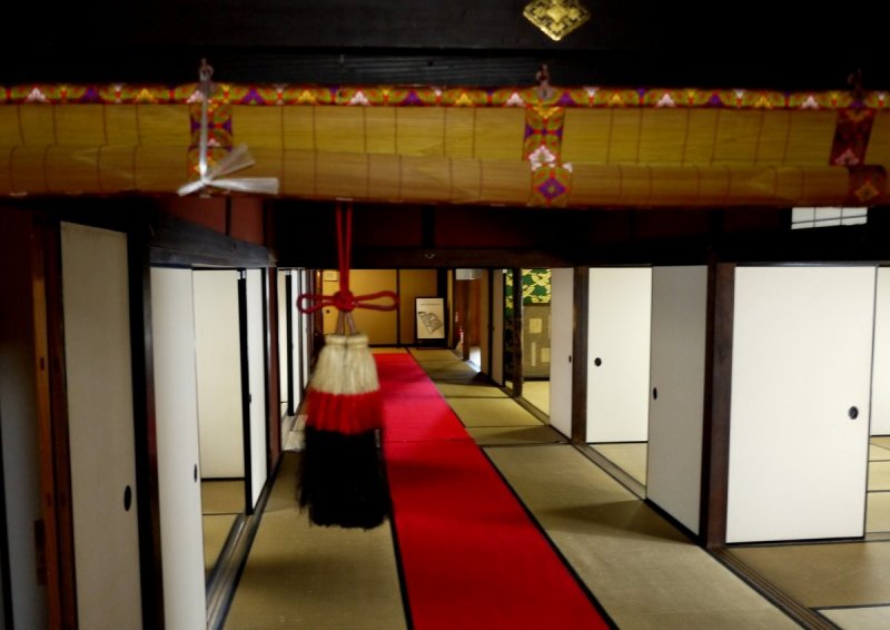 <p>Wide corridor with red carpet between the guest rooms</p>