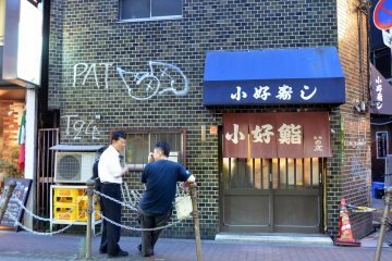 <p>หน้าร้านซูชิ Koyoshi และลูกค้าที่รออยู่ข้างนอก</p>