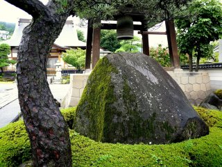 A large mossy rock stands beside the bell tower