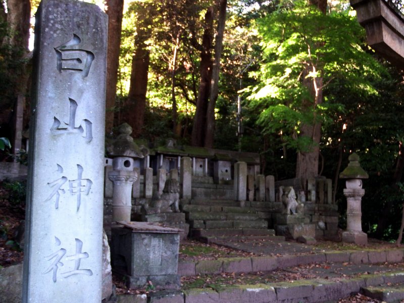 <p>Stone marker of Hakusan Shrine with lined tiny stone shrines in the background</p>