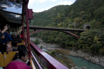 <p>มุมนี้รถไฟสายโรแมนติก Sagano Romantic Train จะผ่านสะพานข้ามแม่น้ำโฮะซึ (Hozugawa River) ซึ่งเป็นสะพานของรถไฟ&nbsp;JR Sanin Main Line ที่ให้บริการอยู่ในเส้นทางปัจจุบัน</p>