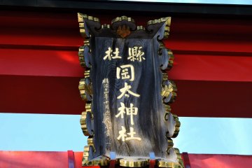 <p>Signboard of Okafuto Shrine hanging on the red torii gate</p>