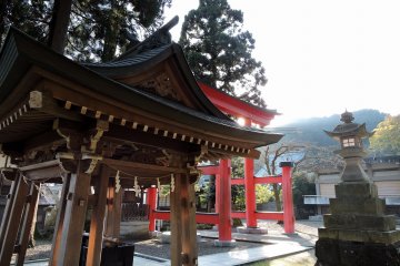 <p>Water purification font, a stone lantern and the red torii gate at Okafuto Shrine</p>
