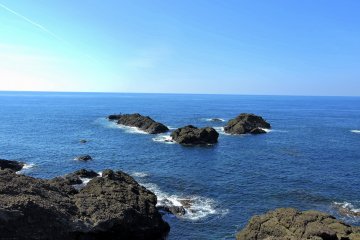 <p>Dark rocks jutting out from the blue sea</p>