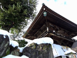雪の積もった岩を足元に聳え立つ、聖玄寺山門