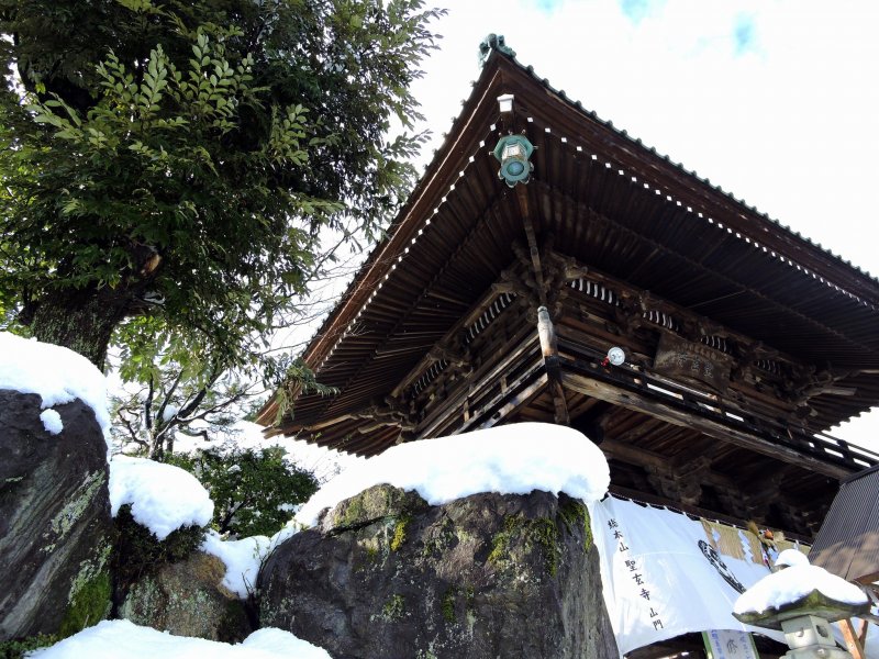 <p>Main gate with snow-capped rocks beside it at the entrance to Shougenji Temple in Fukui</p>
