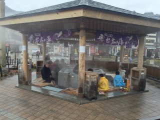 Trước tiên, bạn đến Kinugawa Onsen bắt tàu đến Yunishigawa Onsen. Và nếu bạn đã dành 2h đi tàu từ đây, bạn có thể cảm thấy đói và mệt mỏi. Tại sao không đi mua vài manju (bánh bao nhỏ với nhân đậu đỏ), vẫn còn tươi và ấm, từ một trong những cửa hiệu gần nhà ga? Sau đó, đi đến bể ngâm chân với nước ấm bên ngoài ga.