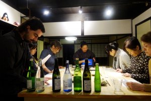 Botol-botol sake menmpati posisi yang mencolok pada meja di workshop mencicipi sake di Kafu