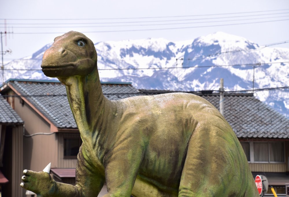 A life-size dinosaur replica in front of the station watching over the traffic and passersby