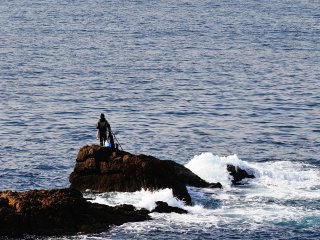 The view from Kikaigaura Observation Deck with a fisherman on a rock in a calm sea