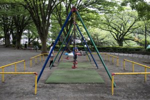 Children playing at one of many swing sets and playgrounds in the park.