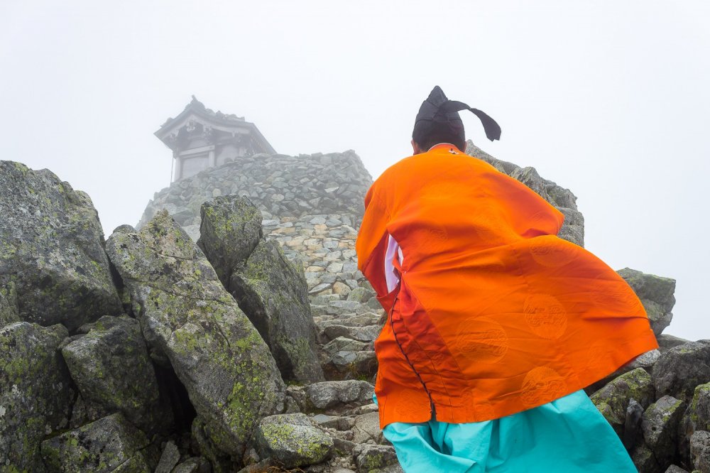 A Shinto priest ascends the final steps to the summit