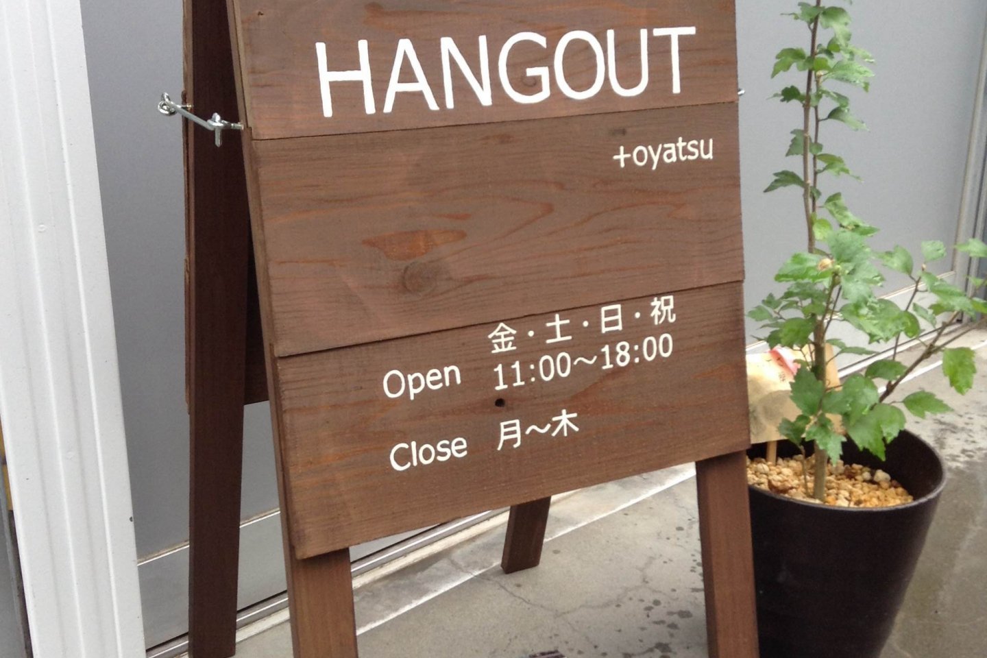 A wooden sign marks Cafe Hangout on quiet Kuritsubo Street.