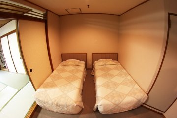 방의 다른 쪽에는 두 개의 서양식 침대와, 작은 탁자, 의자 두 개, 그리고 작은 냉장고가 있다.