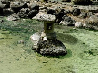 Une lanterne en pierre rugueuse s'élève dans le ruisseau