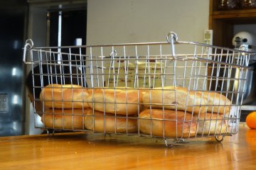 <p>A basket of freshly-baked plain bagels</p>
