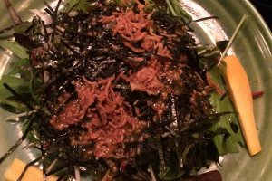 This is a salad with fried onion, seaweed, greens and carrots.
