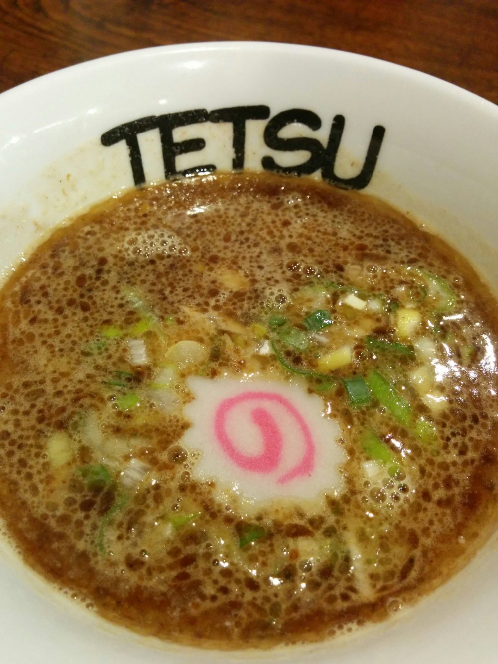 Tsukemen broth topped with pink and white naruto (a kind of fish cake)