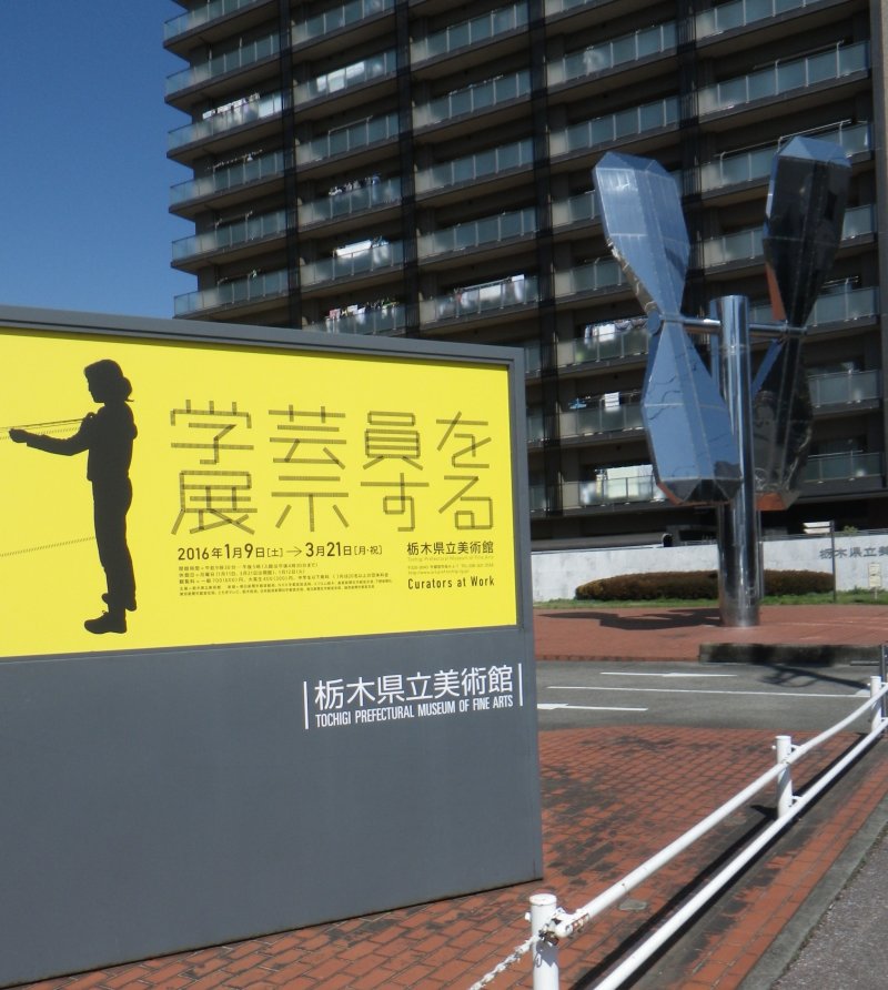 Each temporary exhibition lasts about two months. The poster for this one, Curators at Work, is black and yellow. Posters around town advertise the current exhibition. In the background, is a huge propeller installation which turns when it catches a breeze