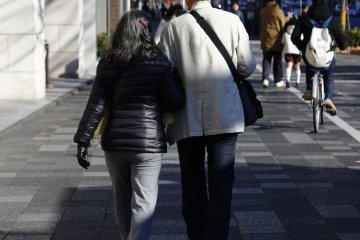 An old couple with a romantic vibe walking towards the Kyoto City Hall area in winter