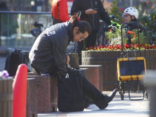 Seorang pemuda bergaya Rockabilly terlihat di depan Balai Kota Kyoto, sedang memasang iPhonenya ke sebuah pengeras suara portable