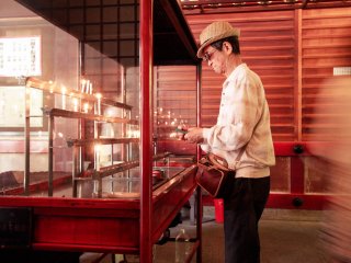 Seorang pria menyalakan lilin di dalam Aula Ichigandou