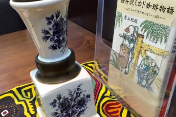 เครื่องบดกาแฟอีกอันหนึ่งพร้อมกับหนังสือเกี่ยวกับ มิคะโดะ ในคะรุอิสะวะ