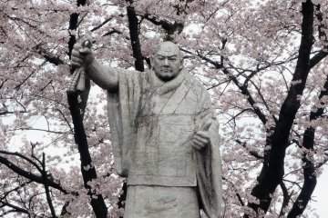 A statue of Nichiren surrounded by blossoms