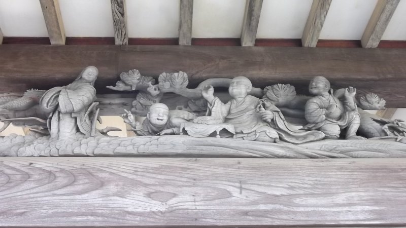 A carved diorama under the eaves of the worship hall